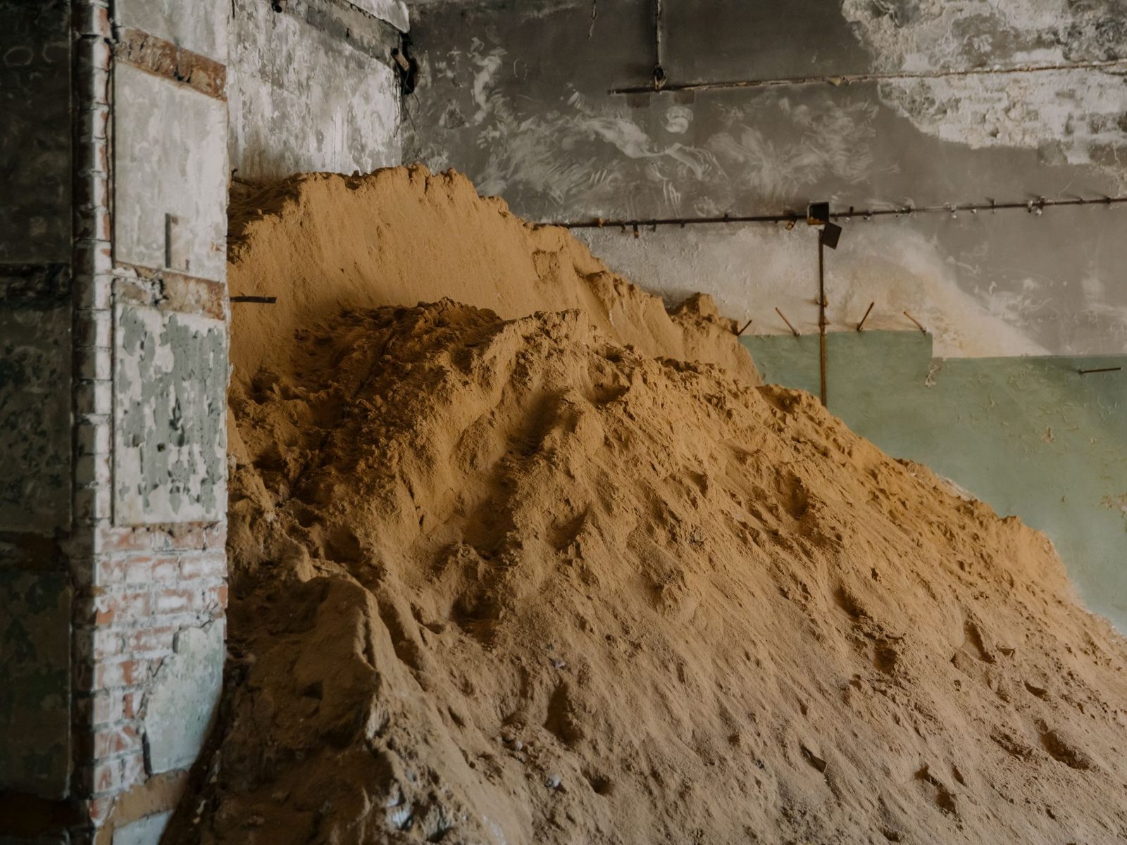 Bulk pile of tan bentonite clay powder in a storage bay