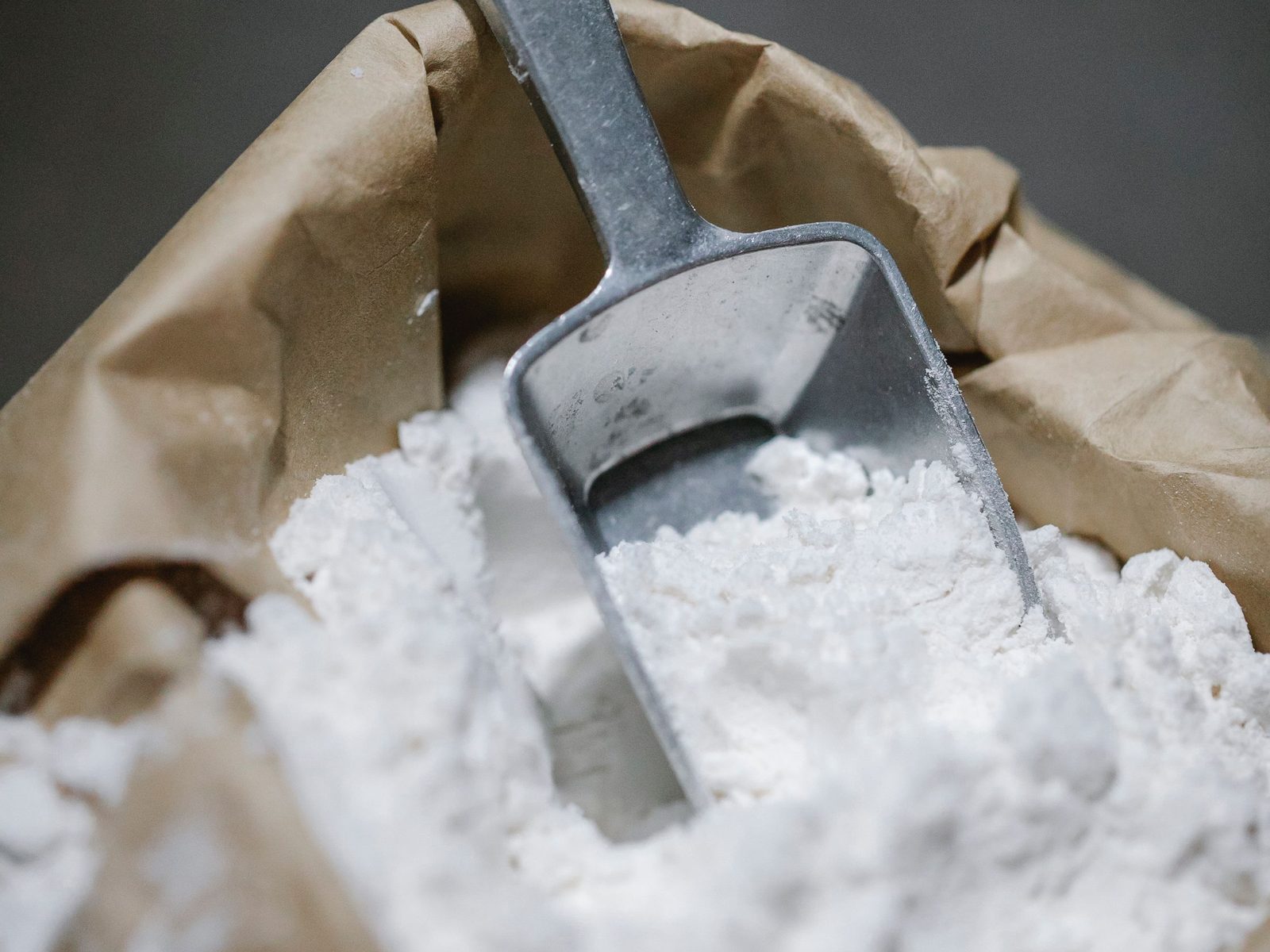 Metal scoop in a sack of ground limestone powder